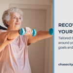 Female physical therapist in a navy polo stands behind elderly female patient raising her arms with blue lightweight dumbbells. Dark text on a pale background reads 