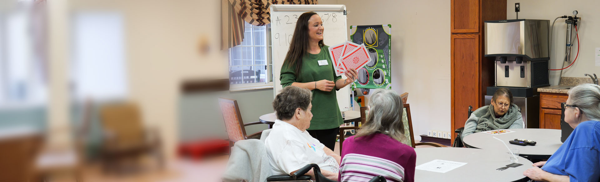 female staff member holds large playing cards with group of seniors